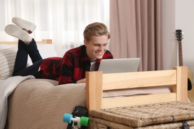 Photo of Online learning. Smiling teenage boy with laptop on bed at home