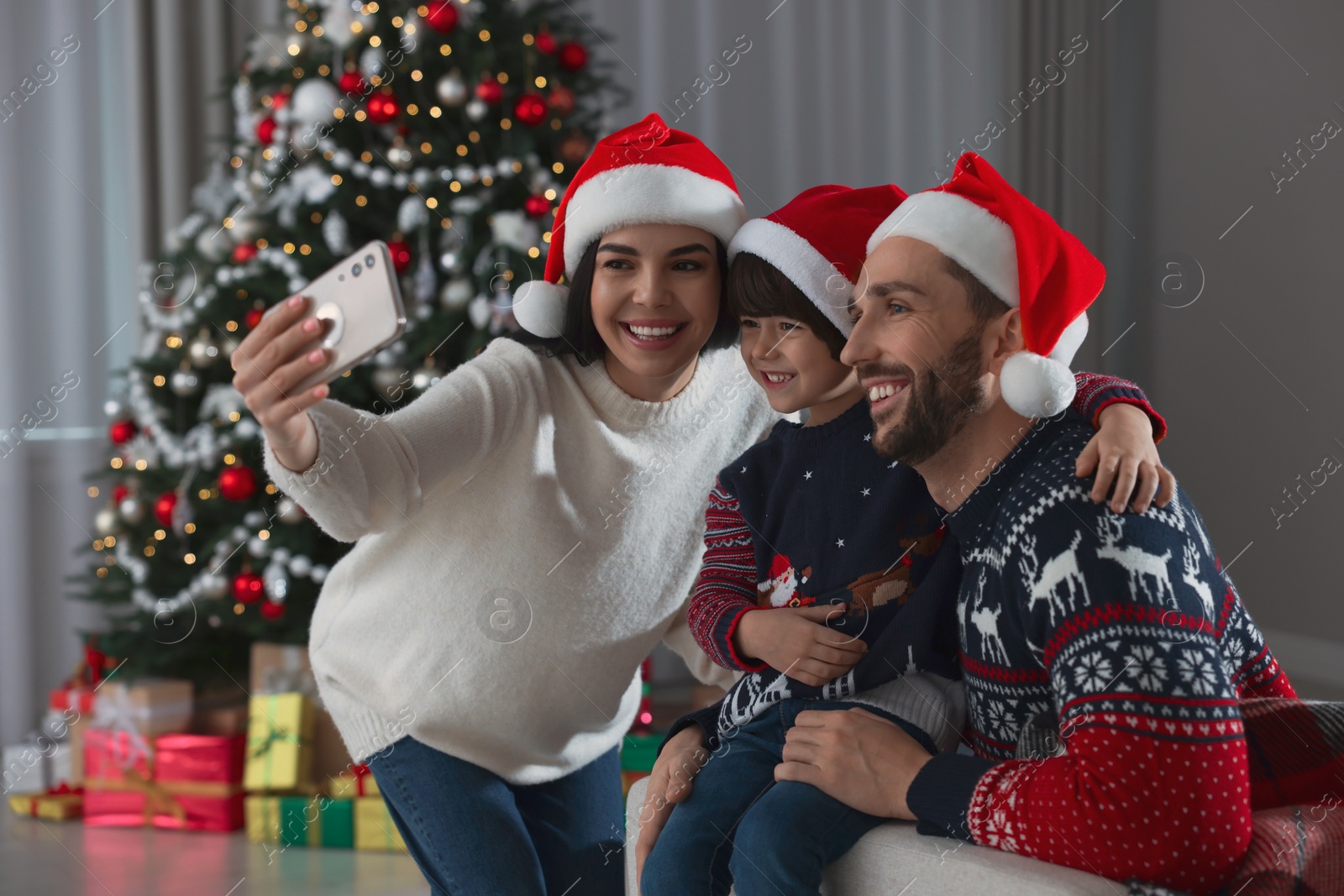 Photo of Happy family in Santa hats taking selfie at home. Christmas celebration