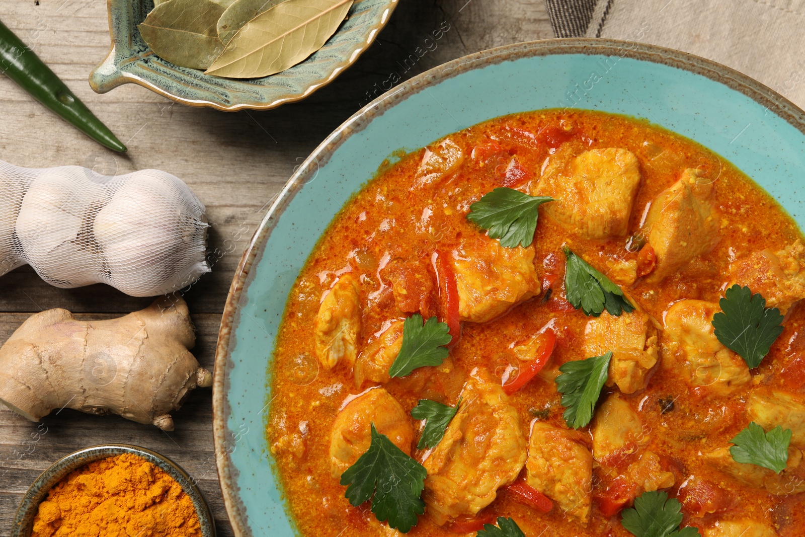 Photo of Delicious chicken curry and ingredients on wooden table, flat lay