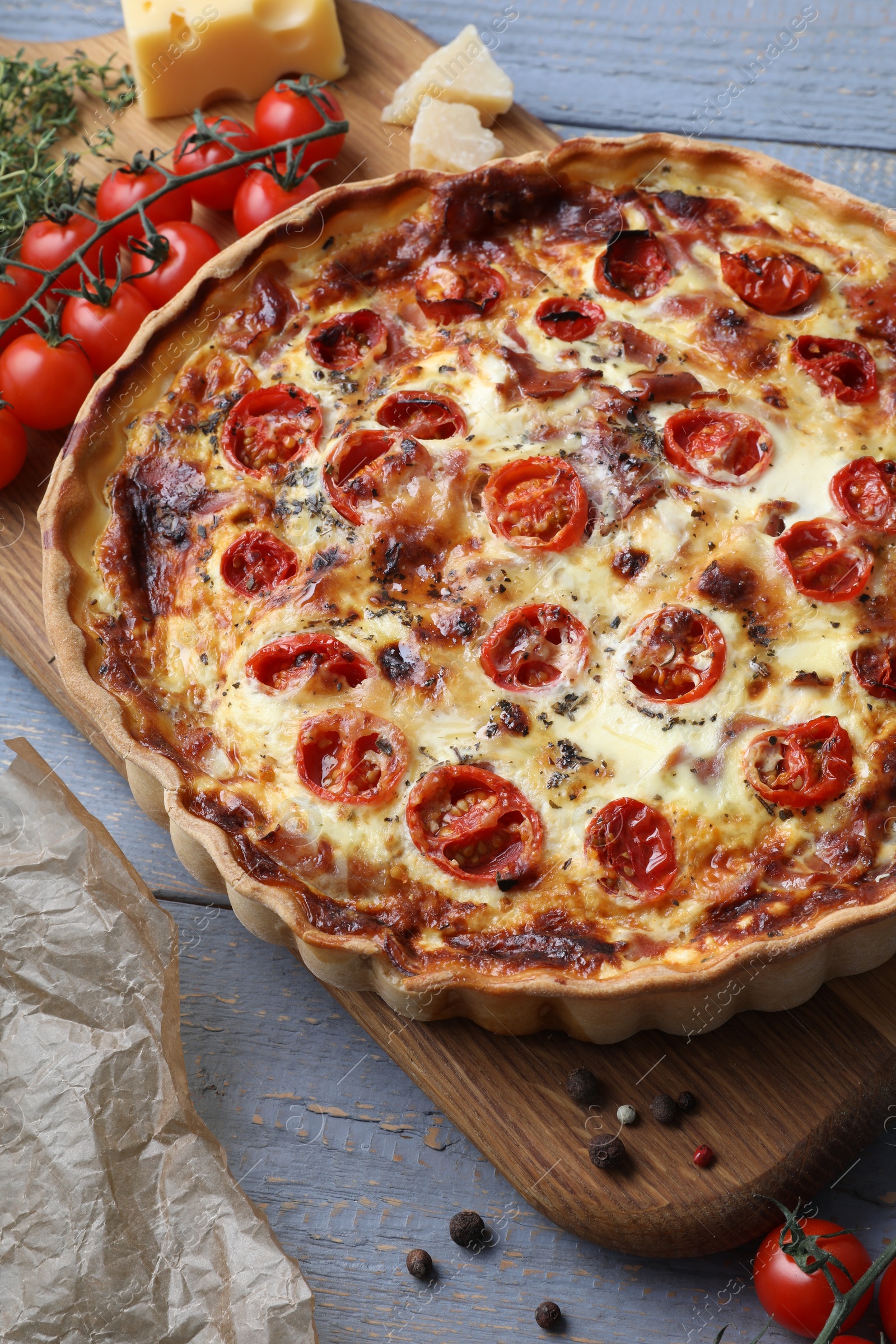 Photo of Delicious homemade prosciutto quiche and ingredients on gray wooden table