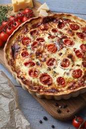 Photo of Delicious homemade prosciutto quiche and ingredients on gray wooden table