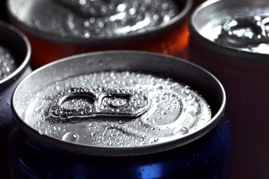 Photo of Aluminum cans of beverage covered with water drops as background, closeup