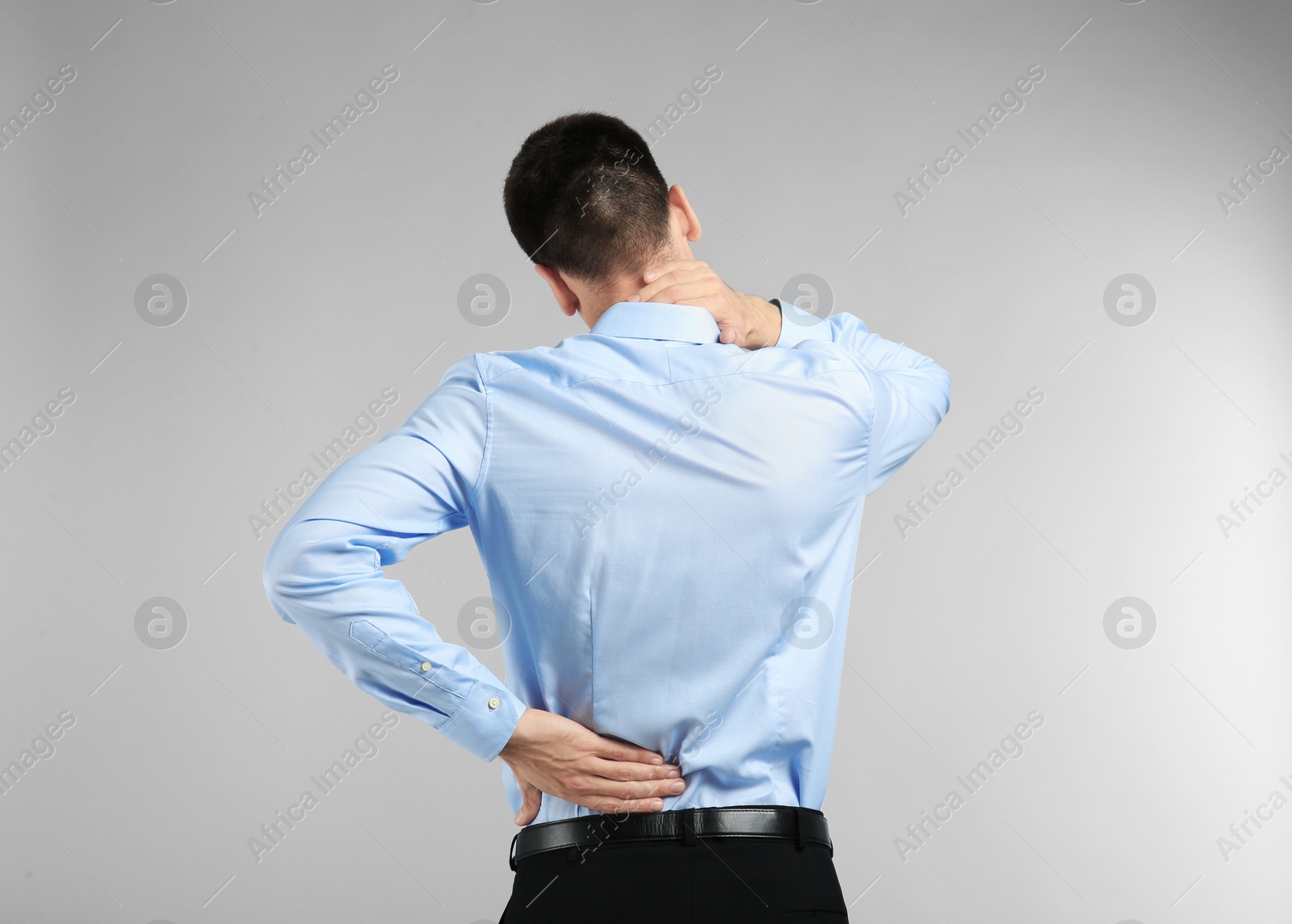 Photo of Young man suffering from back pain on light background