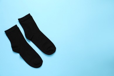 Photo of Pair of black socks on light blue background, flat lay. Space for text