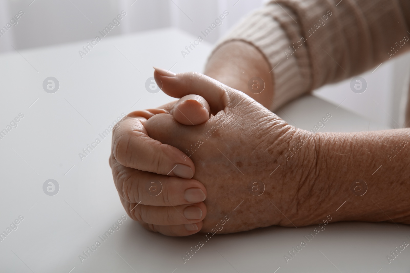 Photo of Elderly woman at white table indoors, closeup