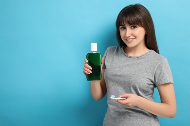 Photo of Young woman with mouthwash and toothbrush on light blue background, space for text