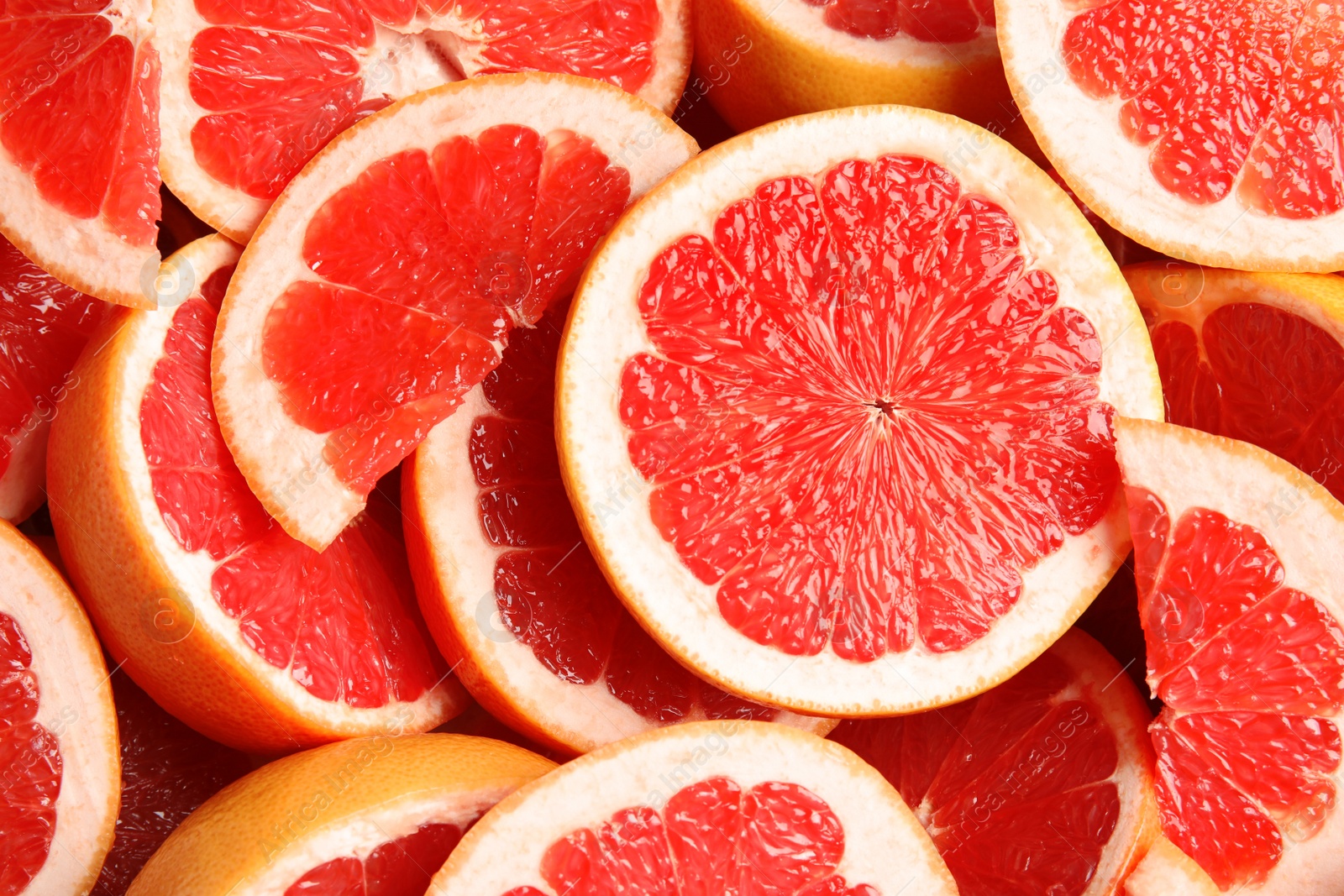 Photo of Many sliced fresh grapefruits as background, top view