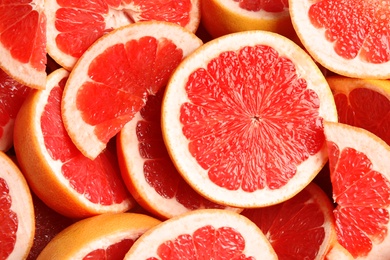 Many sliced fresh grapefruits as background, top view