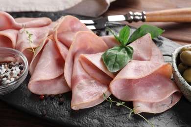 Photo of Tasty ham with basil, sea salt and peppercorns served on table, closeup