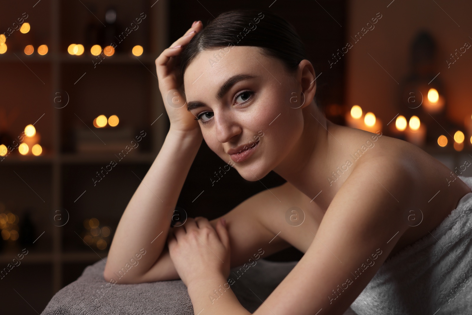 Photo of Spa therapy. Beautiful young woman lying on massage table in salon