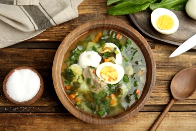 Photo of Delicious sorrel soup with meat and egg served on  wooden table, flat lay