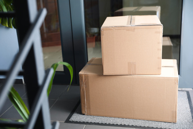 Cardboard boxes on rug near door. Parcel delivery service