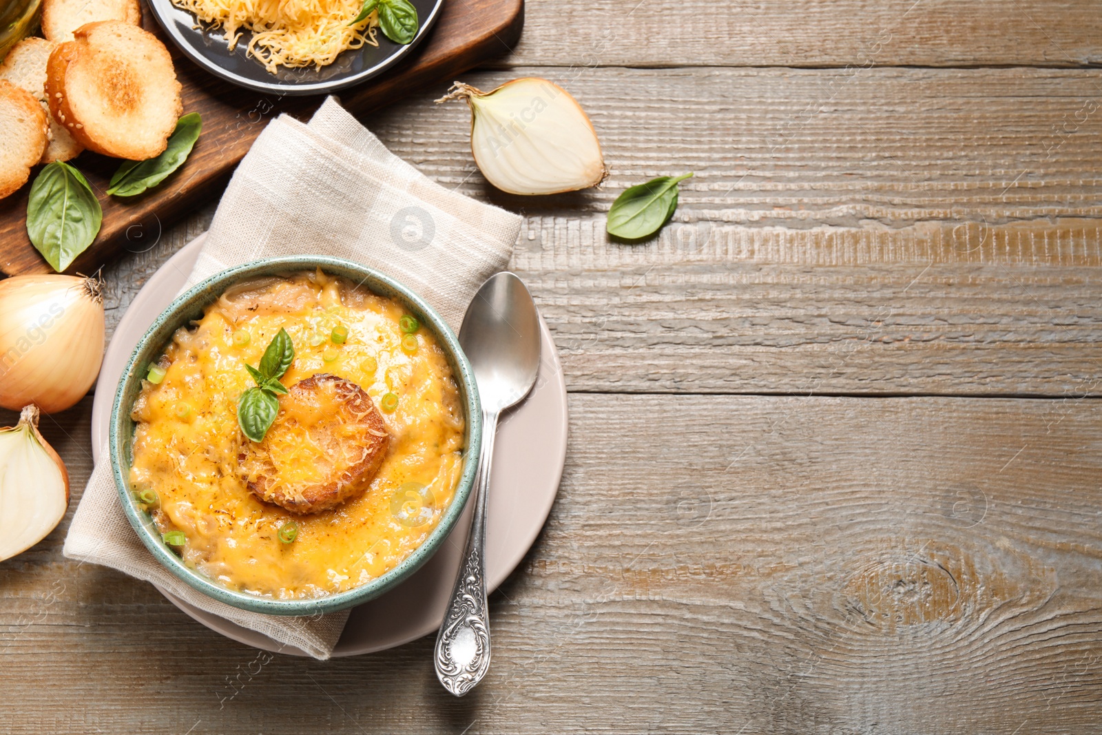 Photo of Tasty homemade French onion soup on wooden table, flat lay. Space for text