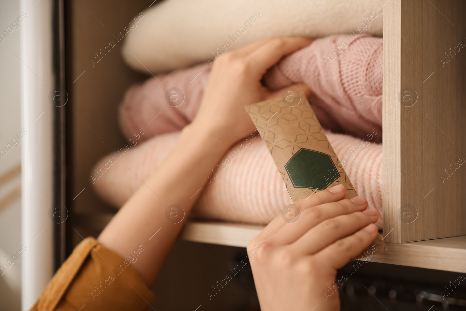 Photo of Woman putting scented sachet in wardrobe, closeup