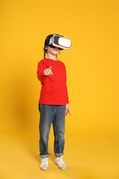 Photo of Little girl using virtual reality headset on yellow background