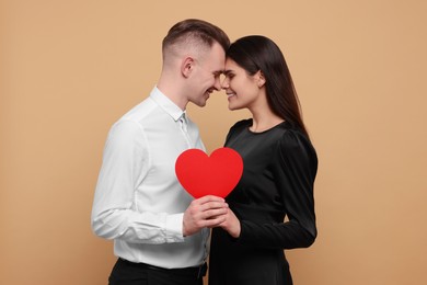 Photo of Lovely couple with decorative heart on beige background. Valentine's day celebration