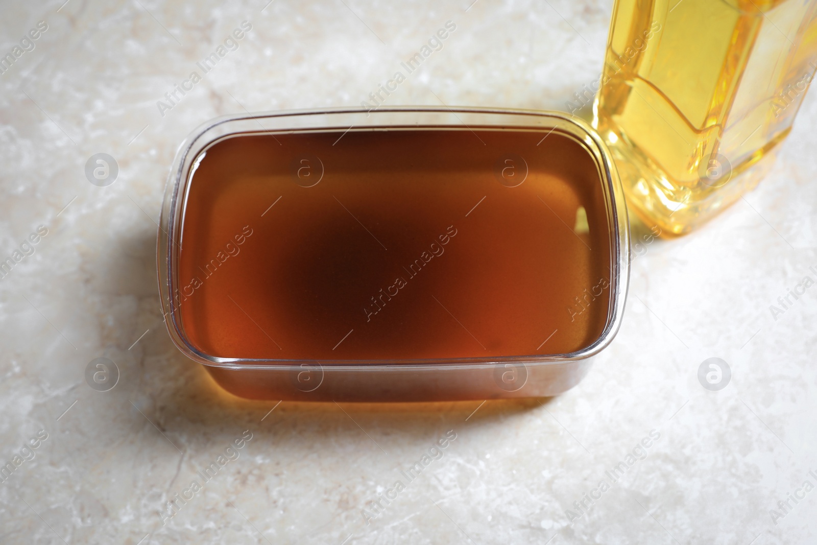 Photo of New and used cooking oil on beige marble table, above view