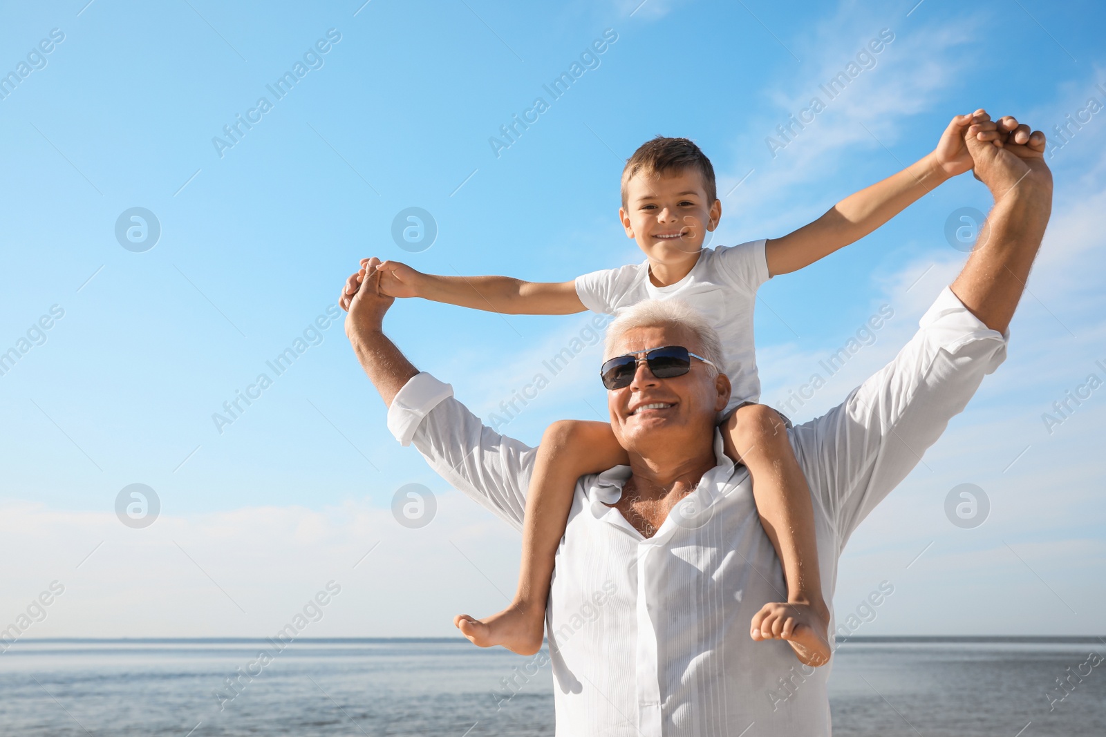 Photo of Cute little boy with grandfather spending time together near sea