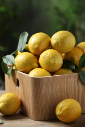 Fresh lemons in crate on wooden table, closeup