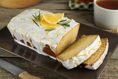 Tasty lemon cake with glaze on wooden table, closeup