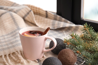 Composition with cup of hot winter drink and plaid near window. Cozy season