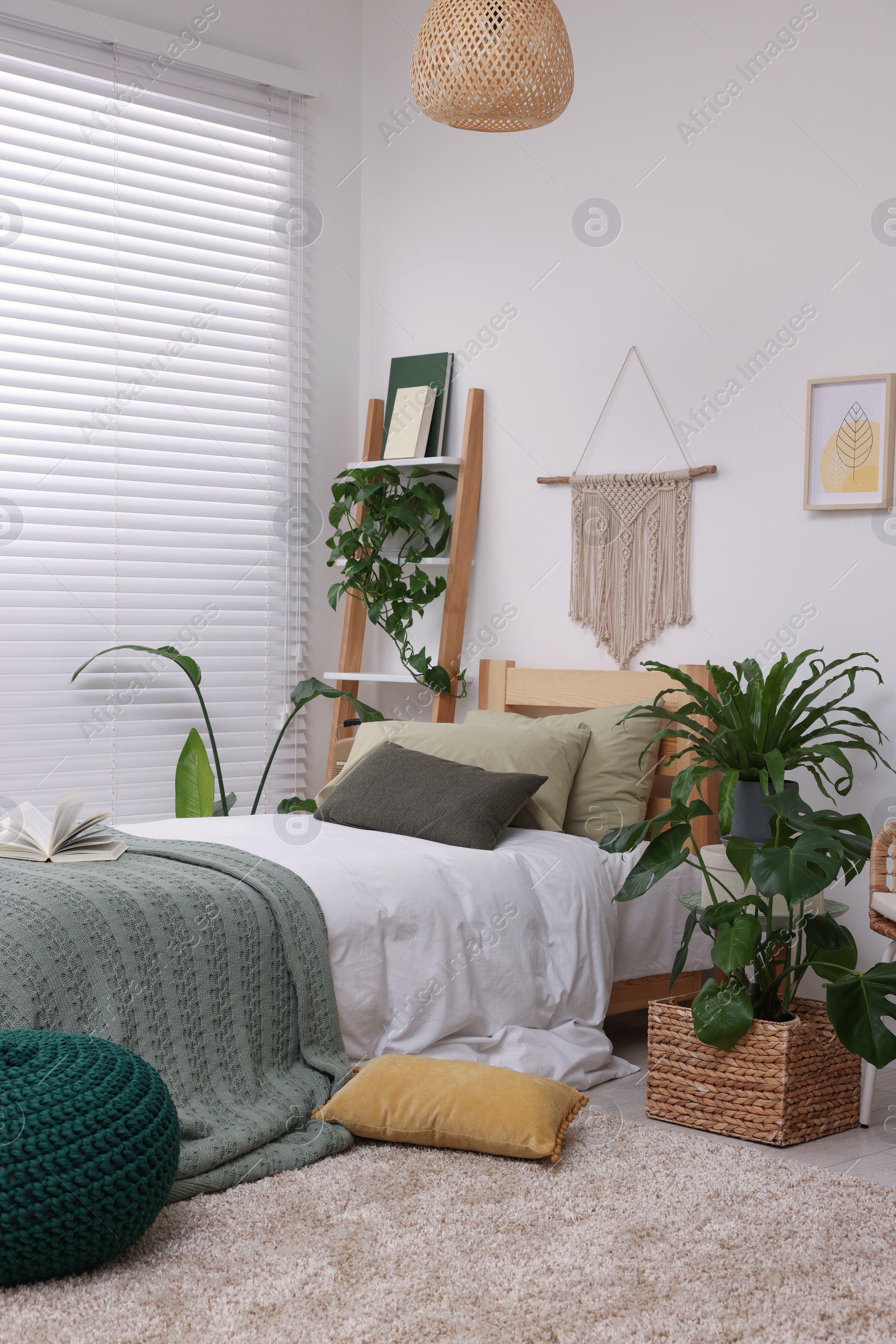 Photo of Large comfortable bed and potted houseplants in stylish bedroom. Interior design