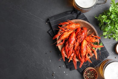 Flat lay composition with delicious red boiled crayfishes on black table, space for text