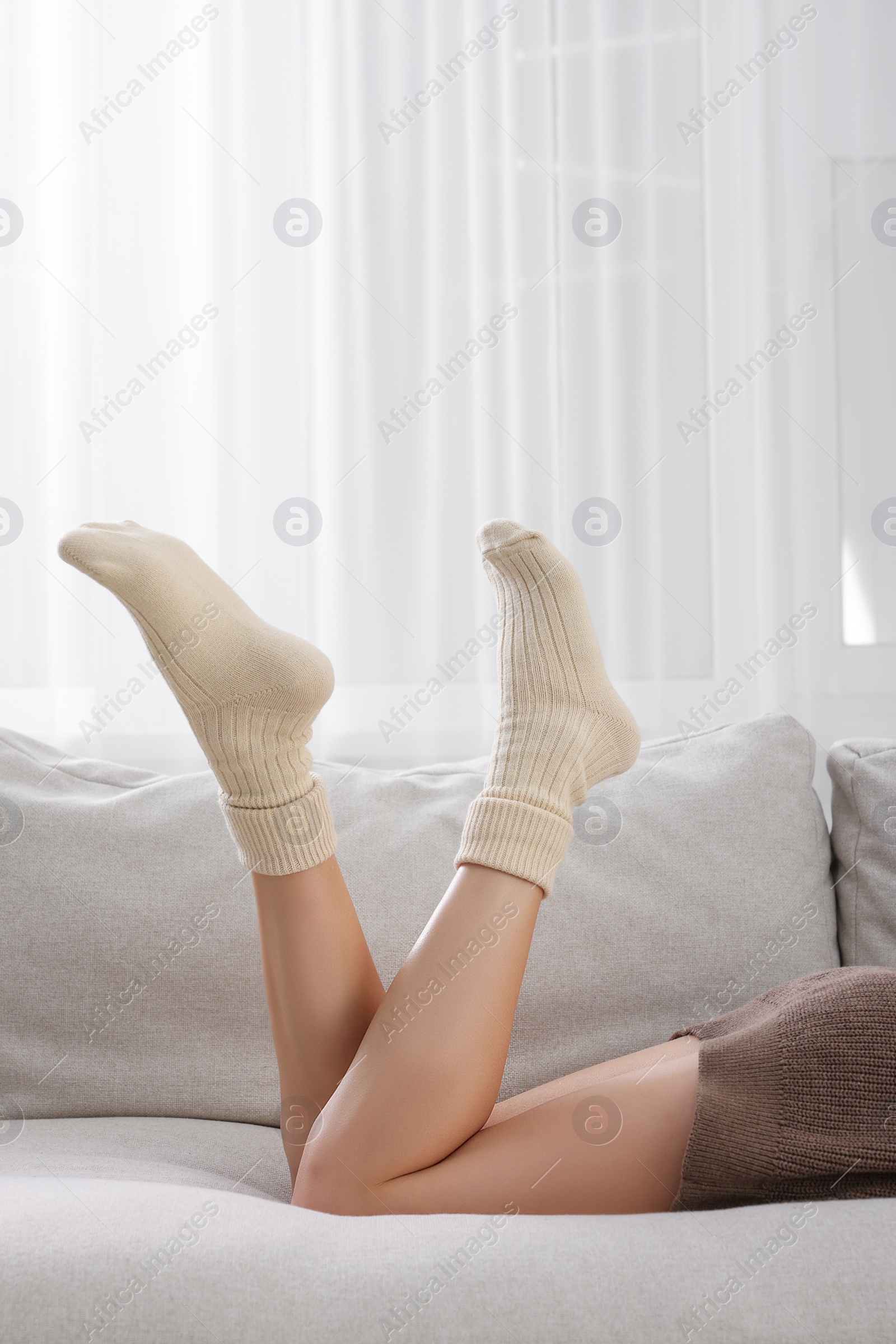 Photo of Woman in warm socks lying on sofa, closeup