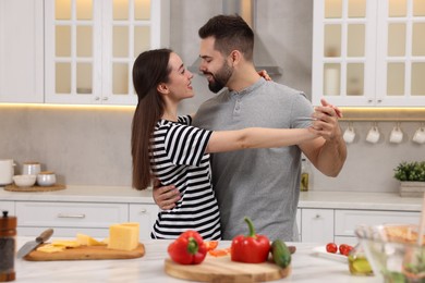 Photo of Happy lovely couple dancing together while cooking in kitchen