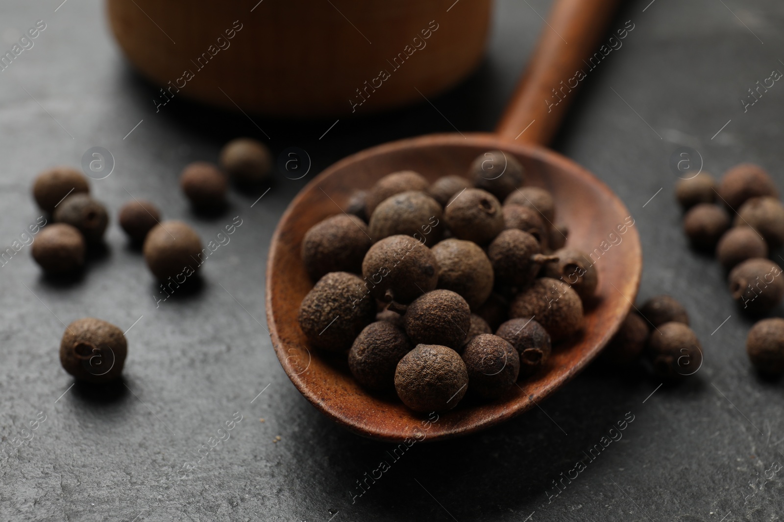 Photo of Dry allspice berries (Jamaica pepper) on black table, closeup