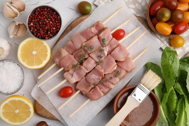 Photo of Flat lay composition of skewers with cut raw meat, thyme, tomatoes and marinade on light table