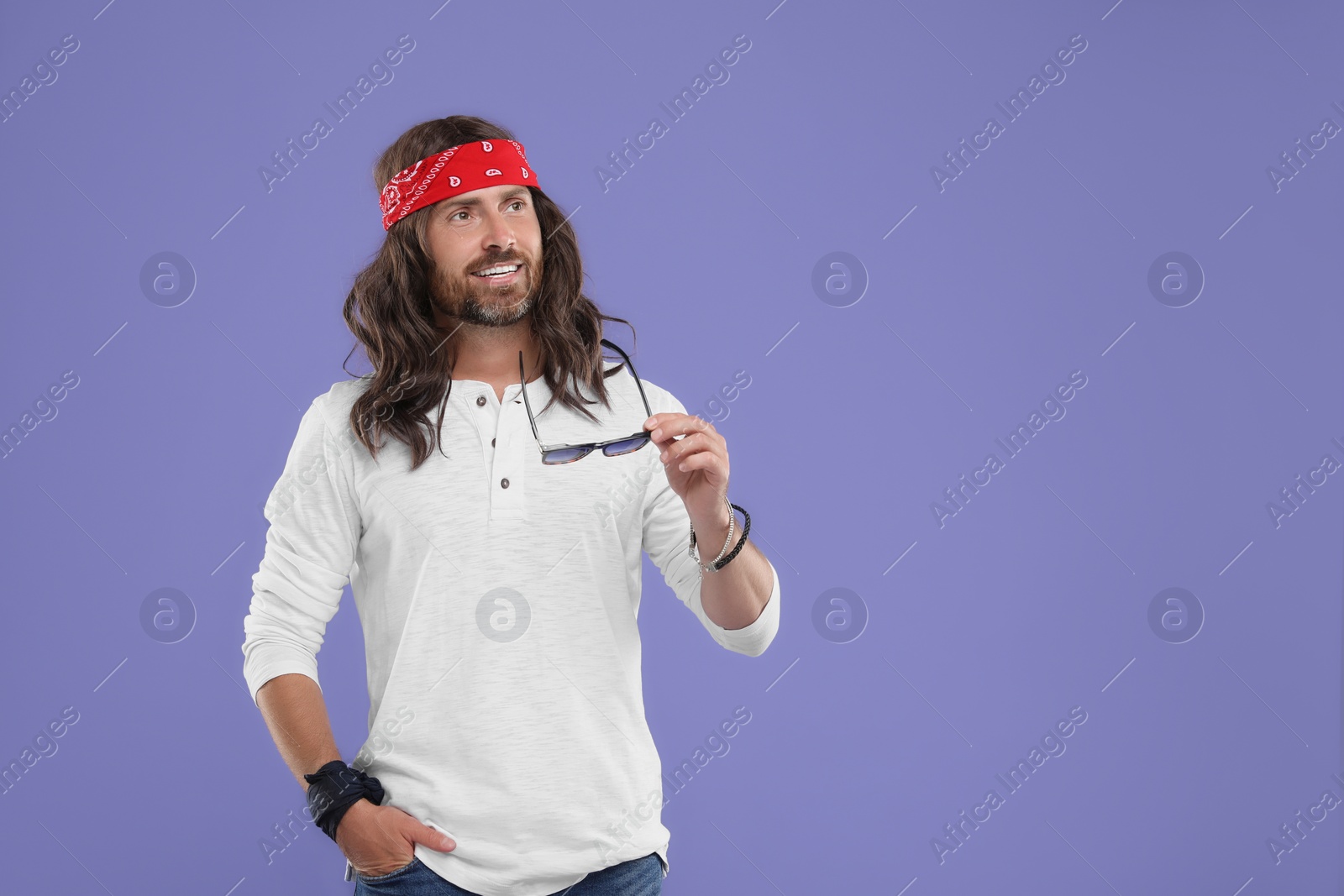 Photo of Stylish hippie man with sunglasses on violet background, space for text