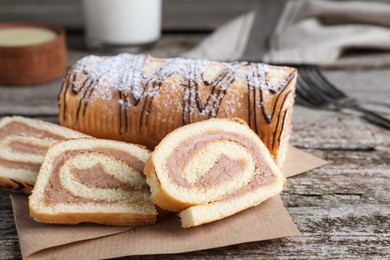 Photo of Tasty cake roll with cream on wooden table, closeup