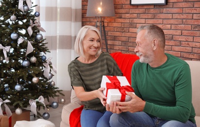 Mature couple with Christmas gift box at home