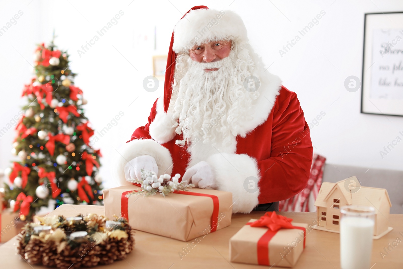 Photo of Authentic Santa Claus wrapping gift at table indoors