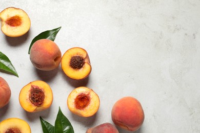 Photo of Delicious juicy ripe peaches and leaves on light grey textured table, flat lay. Space for text