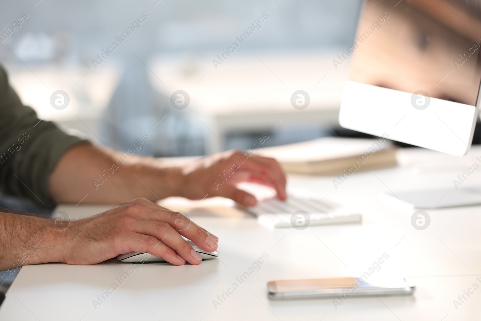 Photo of Man using modern computer at white desk in office, closeup