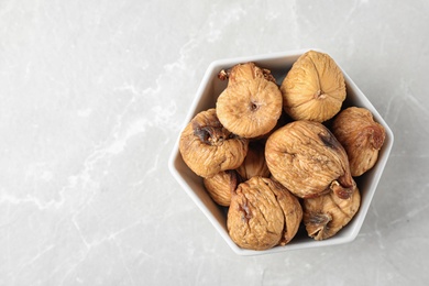 Photo of Bowl of tasty dried figs on light grey marble table, top view. Space for text