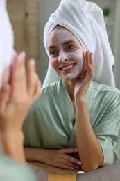Photo of Woman with face mask near mirror in bathroom. Spa treatments