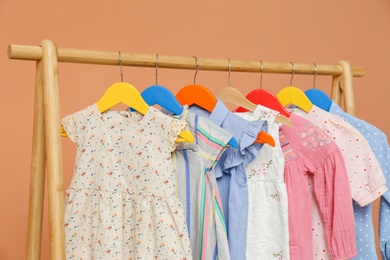 Rack with stylish children clothes on beige background