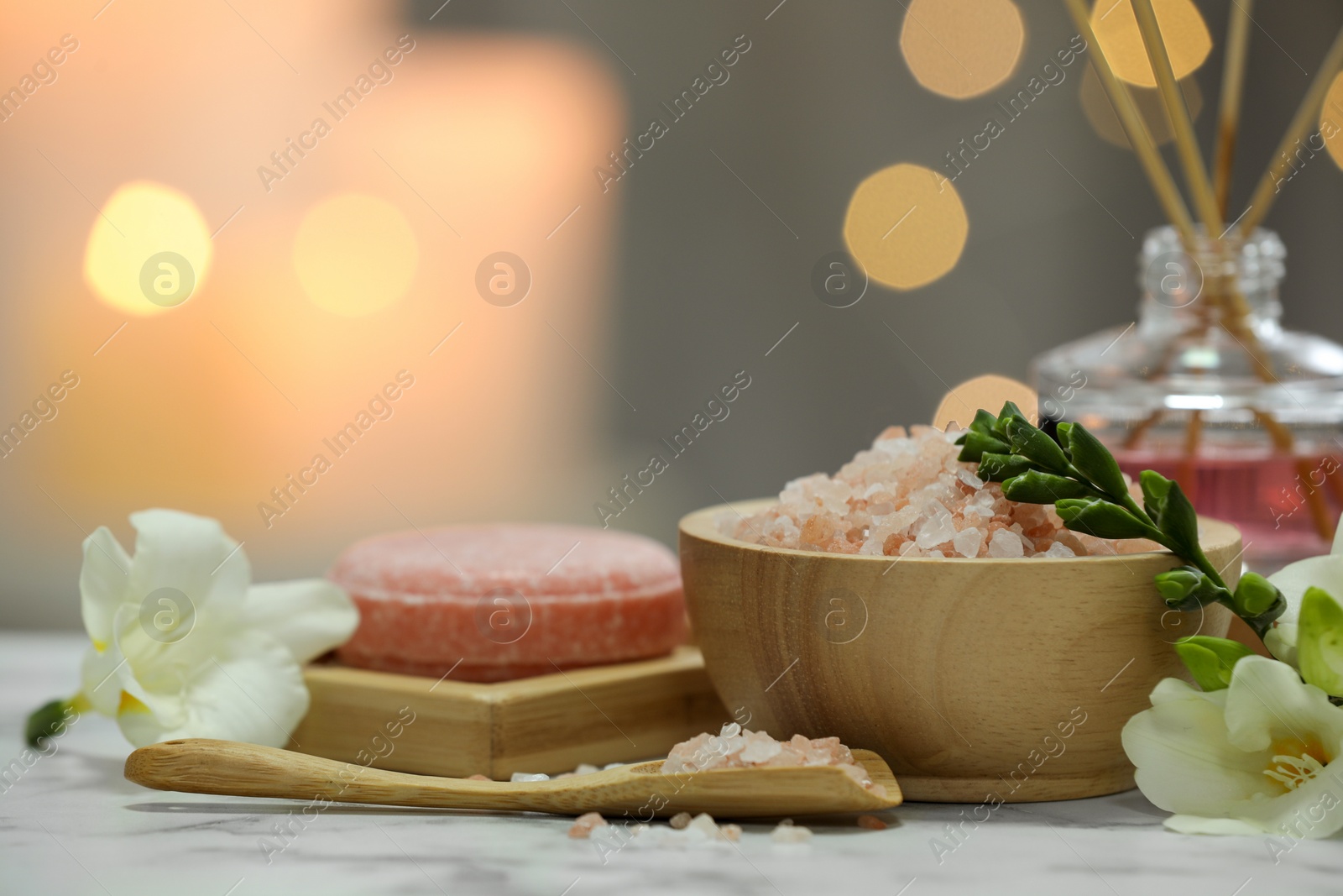 Photo of Beautiful composition with different spa products and flowers on white marble table against blurred background