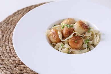 Photo of Delicious scallop pasta with spices in bowl on table, closeup