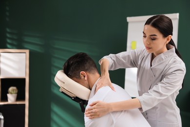 Photo of Man receiving massage in modern chair indoors