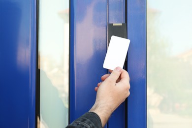 Photo of Man opening magnetic door lock with key card outdoors, closeup