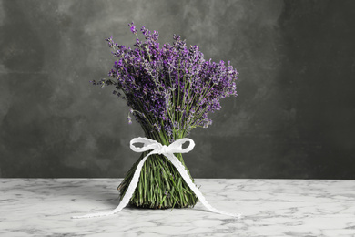 Photo of Beautiful lavender bouquet on white marble table against grey background