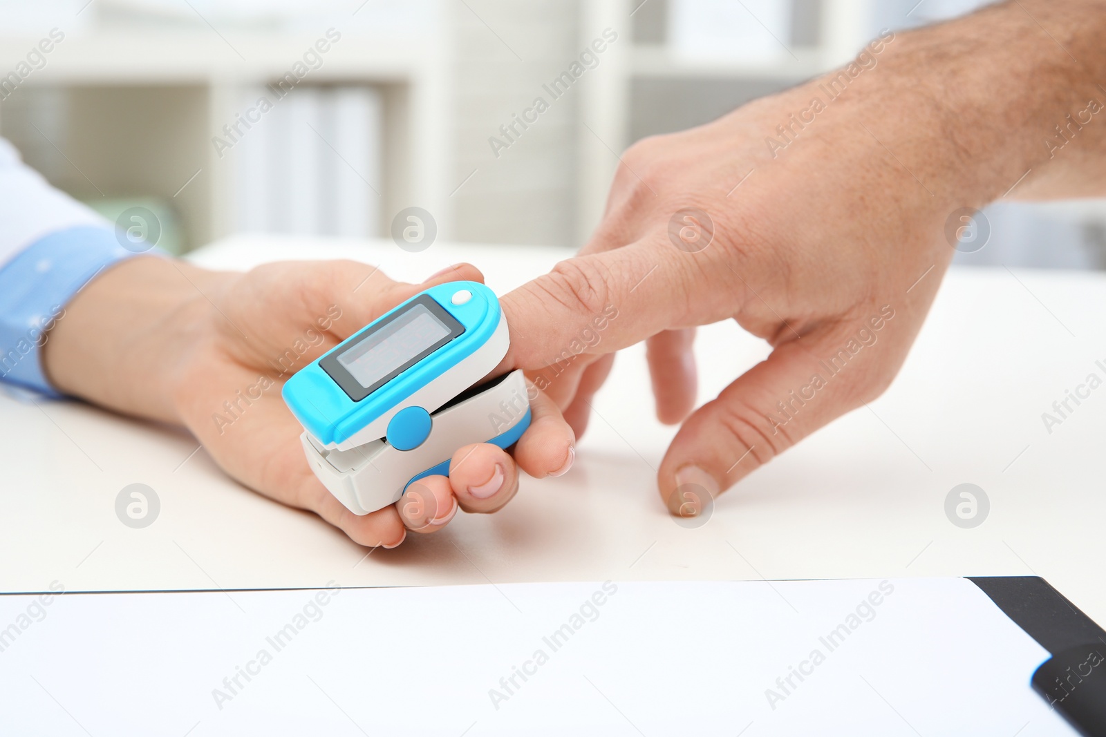 Photo of Doctor checking mature man's pulse with medical device in hospital, closeup