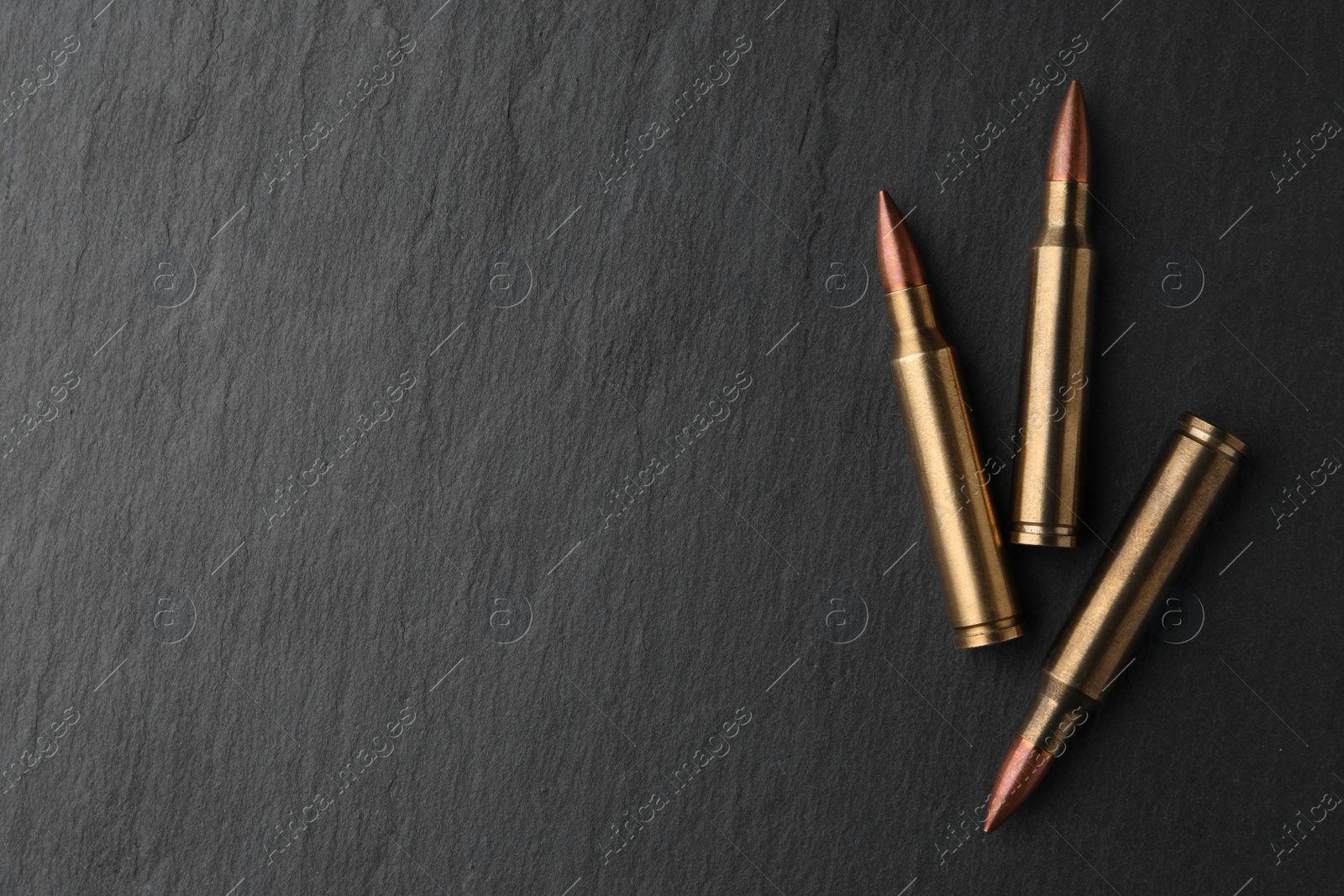 Photo of Many bullets on black table, flat lay. Space for text