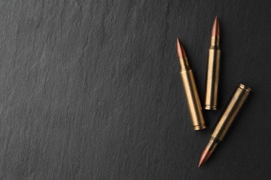 Photo of Many bullets on black table, flat lay. Space for text