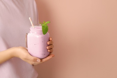 Woman holding mason jar with fig smoothie on pink background, closeup. Space for text