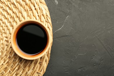 Photo of Soy sauce in bowl on black textured table, top view. Space for text